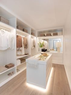 an image of a white closet with clothes on shelves and lights in the corner,