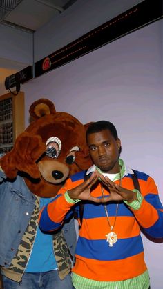 two men standing next to each other in front of a teddy bear