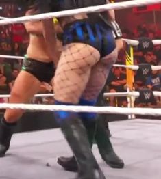 two women in fishnet stockings are wrestling with each other on the ropes at an indoor event