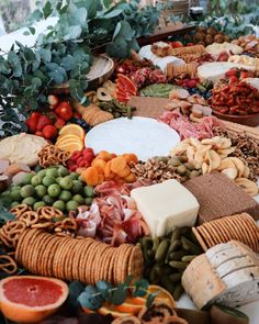 an assortment of cheeses, meats and fruits arranged in a circle on a table