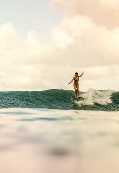 a woman riding a wave on top of a surfboard in the middle of the ocean