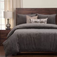 a bed with grey and white comforter in a bedroom next to two lamps on either side of the bed