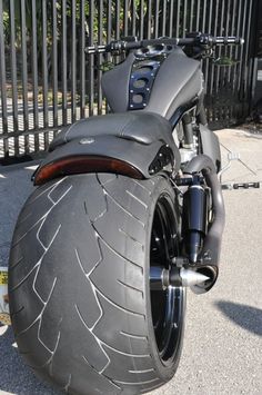 a close up of a motorcycle parked on the side of the road next to a fence