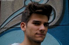 a young man standing in front of a wall with a blue and gray design on it