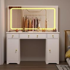 a white dresser with a mirror and clothes hanging on the rack in front of it