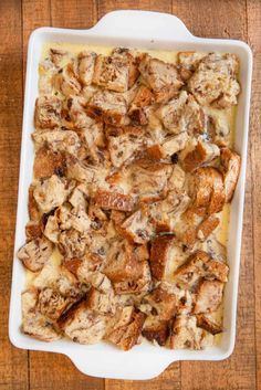 a casserole dish filled with meat and cheese on top of a wooden table