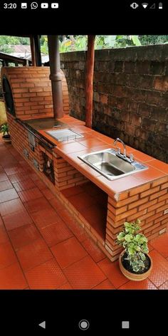 an outdoor kitchen made out of bricks with a sink and oven on the outside wall