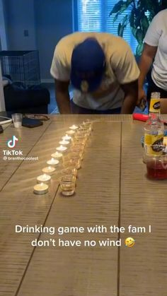 two men sitting at a table with cups and bottles on it that have candles in them