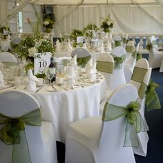 the tables are set with white linens and green bows