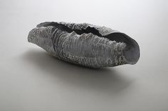 a metal object sitting on top of a white table next to a gray wall and floor