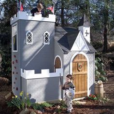 a little boy standing in front of a fake castle with a dog on the roof