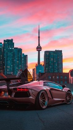 a very nice looking car parked in front of some tall buildings with the sky in the background