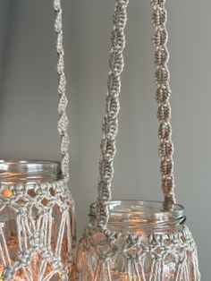 two glass jars with string hanging from the top and bottom, one is filled with lights