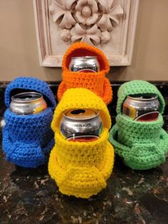 four crocheted can cozyies sitting next to each other on top of a counter