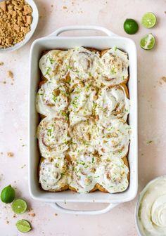 a casserole dish filled with sour cream and topped with limes, sits on a pink surface