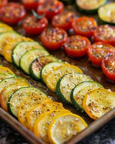 sliced zucchini and tomatoes on a tray ready to be cooked in the oven