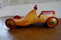 an old wooden toy car sitting on top of a wood table next to a wall