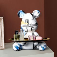 a teddy bear sitting on top of a plate with nail polish and perfume bottles next to it