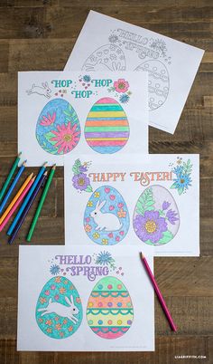 three easter coloring pages with colored pencils and markers on a wooden table next to them