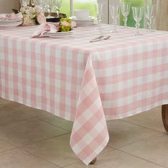 a table with pink and white checkered cloth on it, next to wine glasses