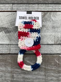 a red, white and blue crocheted towel holder with a button on it