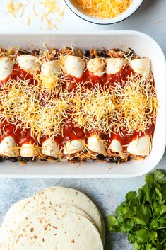 an enchilada with cheese and sauce in a white casserole dish