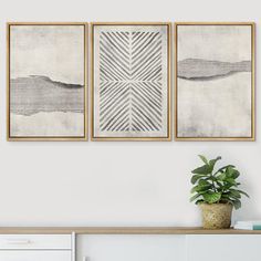 three framed art pieces on a wall above a white dresser with a potted plant