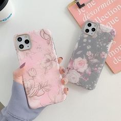 two cases with flowers on them sitting next to each other, one is pink and the other is gray