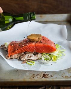 a person pours wine into a plate with salmon and lettuce on it