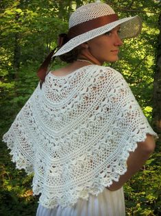 a woman wearing a white crochet shawl in the woods