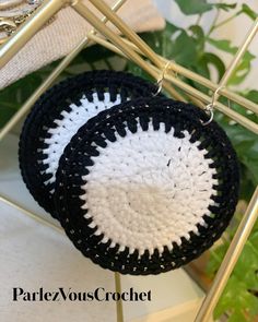 two black and white crocheted baskets sitting on top of a metal rack next to a plant