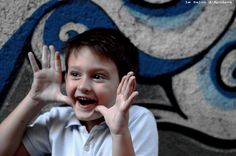 a young boy with his hands up in front of him, smiling at the camera