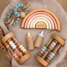 wooden toys are arranged on top of a blanket with a rainbow in the middle and two bottles