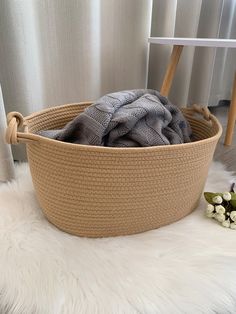 a basket that has some clothes in it on a white fur rug next to a window