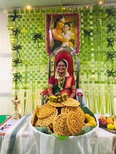 a woman sitting in front of a large display of food on a table with green and yellow wallpaper