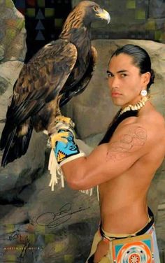 a man with an eagle tattoo on his arm next to a large bird in front of him