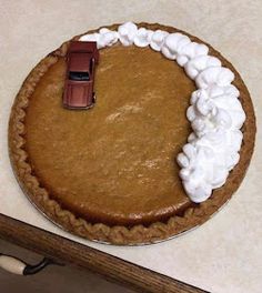 a pumpkin pie with a toy car on top and whipped cream around the crusts