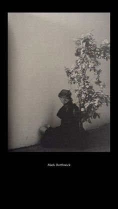 a woman sitting on the ground next to a tree