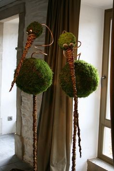 two sculptures made out of grass are sitting in front of a window