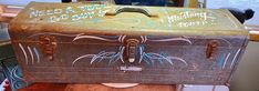 an old trunk with writing on it sitting on a table in front of a window