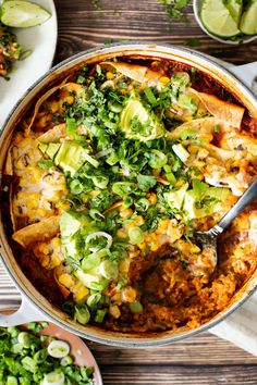 a large pot filled with mexican food and garnished with cilantro, avocado, and tortilla chips