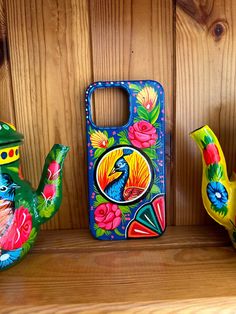 three colorful teapots are sitting on a shelf next to a cell phone case