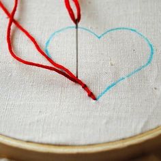 a heart is drawn on a piece of fabric with a needle in the shape of a heart