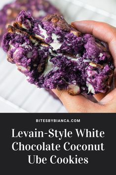 a person holding up a purple cookie with white chocolate and blueberries on it, in front of the words leviin - style white chocolate coconut ube cookies