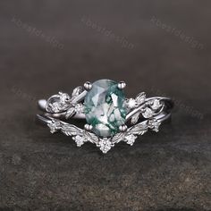 an oval cut green and white diamond ring with leaves on the band, set in 18k white gold