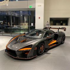 an orange and black sports car in a showroom