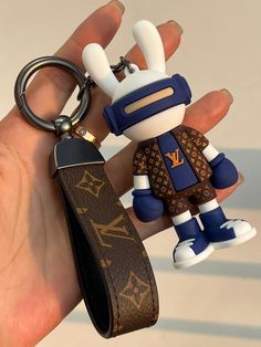 a hand holding a keychain with a cartoon figure on it's side