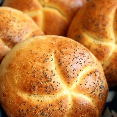 bread rolls with poppy seed sprinkles sitting on a blue and white cloth