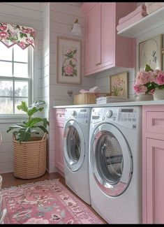 a washer and dryer in a small room with pink decor on the walls