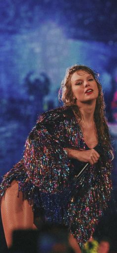 a woman in a sequined dress holding an umbrella and singing into a microphone